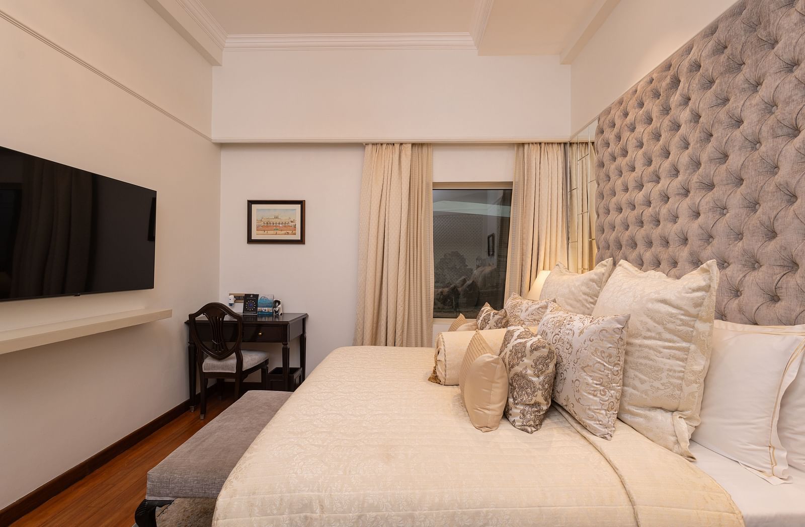 image of a king size bed with well set pillows over at our boutique room with a wall mounted tv - The Claridges New Delhi
