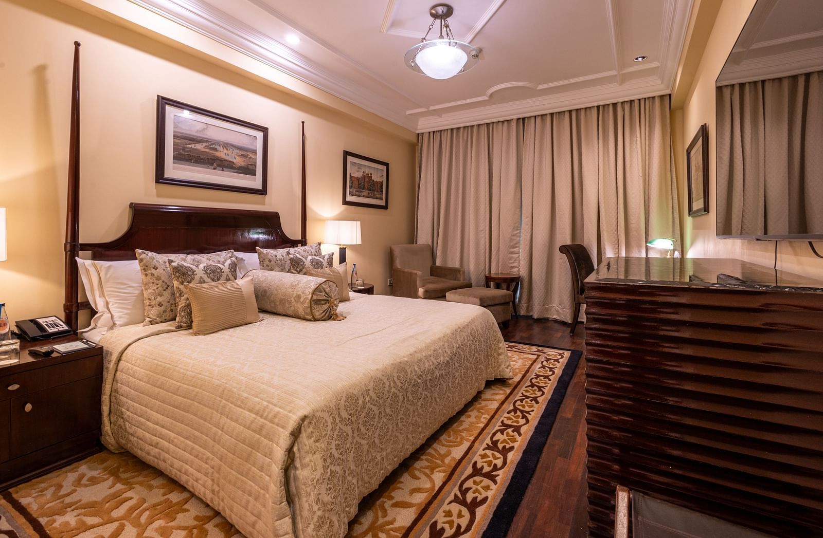 image of the bedroom of the heritage parlour room with a king size bed and beautiful photoframes hung on the wall - The Claridges New Delhi