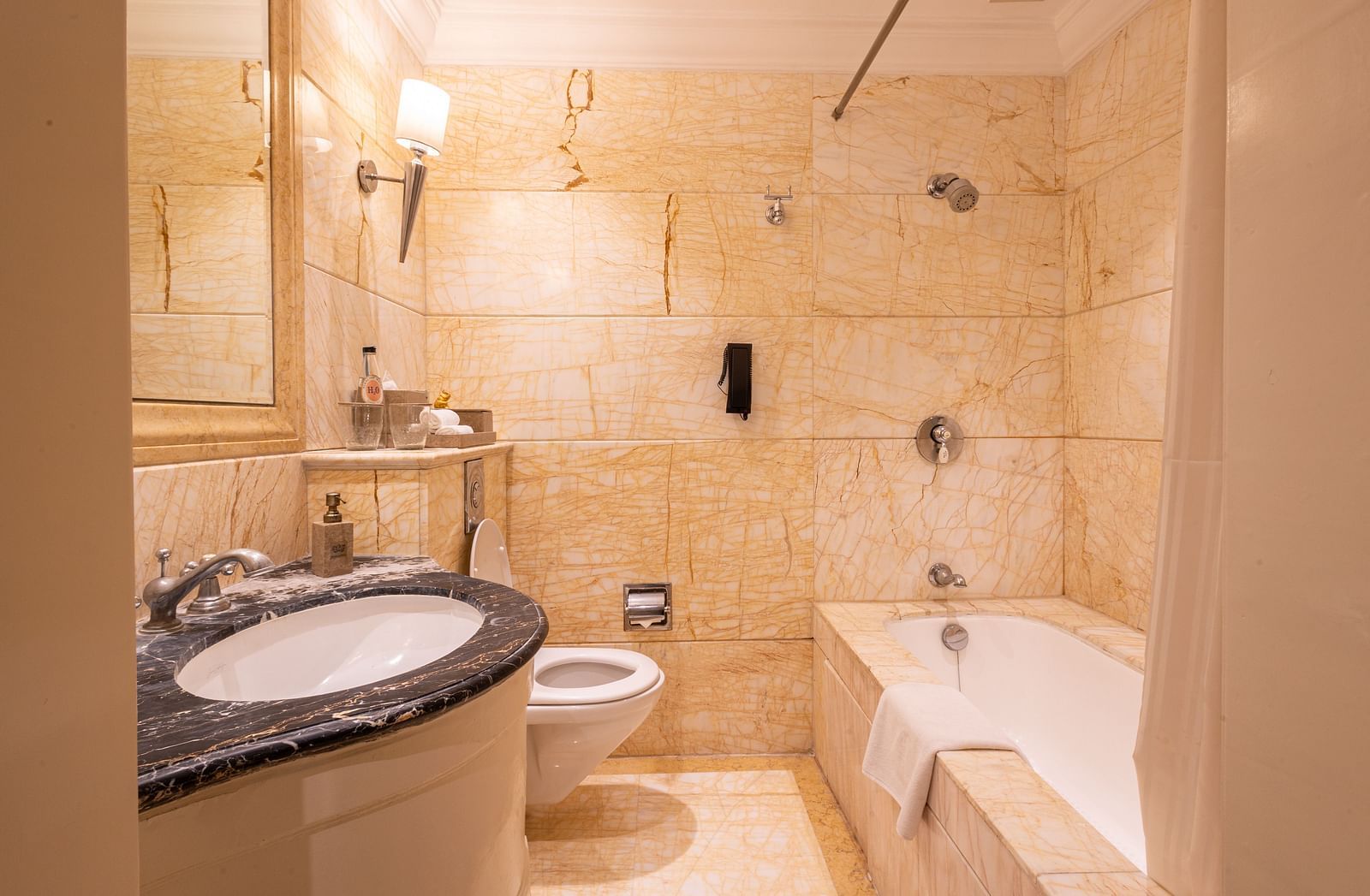 image of a well appointed bathroom with a wash basin and bathtub and a commode at the far corner of out heritage parlour room -The Claridges New Delhi