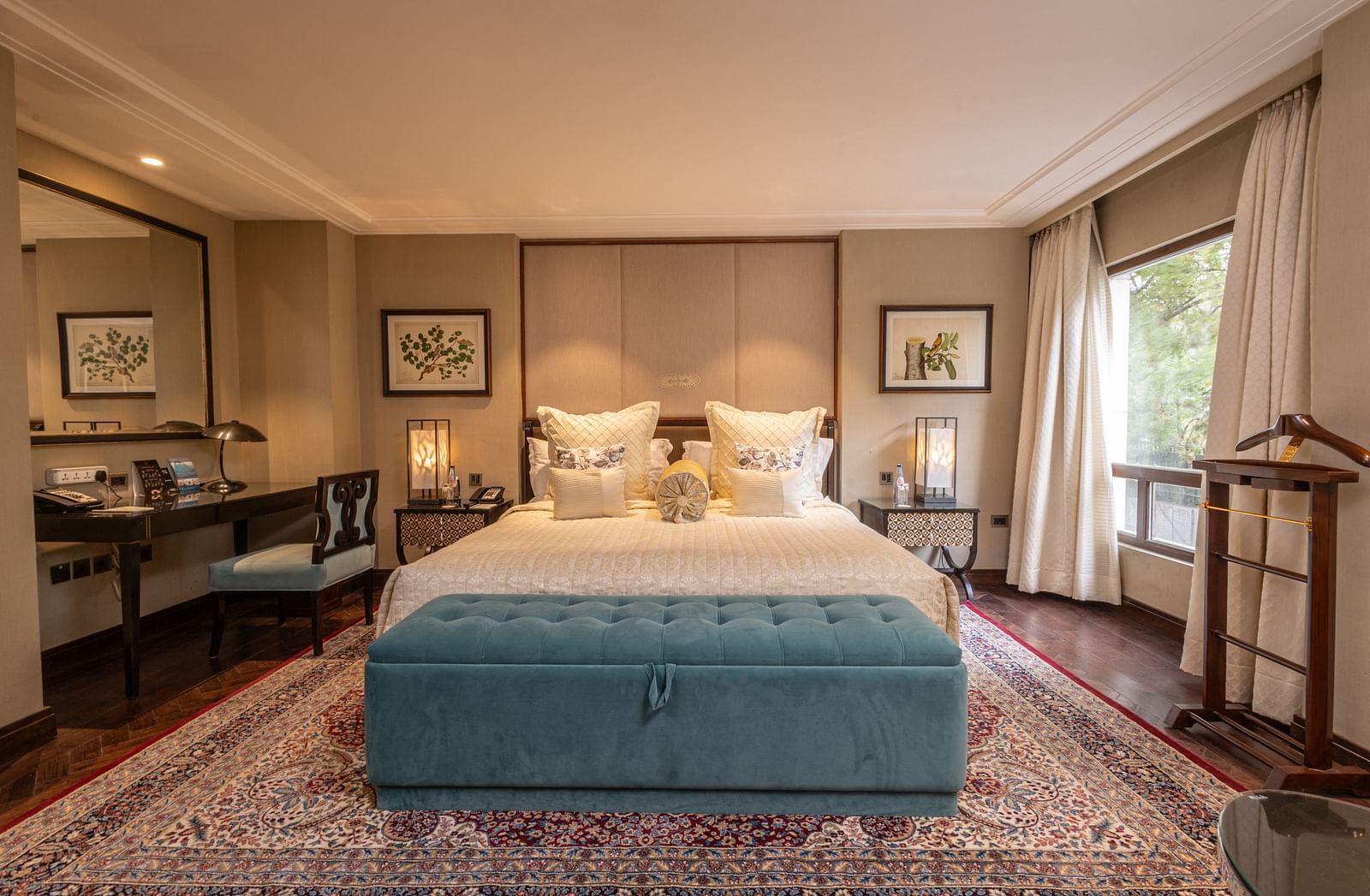 Image of the Cabana Room highlighting stylish interiors, with a king-size bed and a contemporary blue seating area situated in front of the bed - The Claridges New Delhi