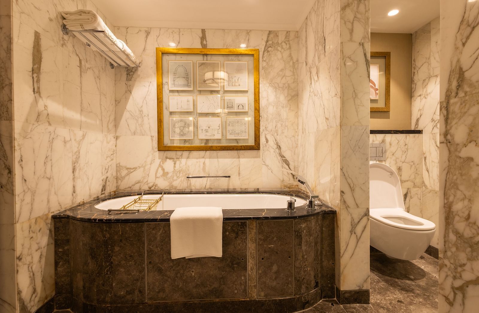 image of a bathtub with elegant washroom fittings at the cabana room - Image of the Cabana Room featuring upscale interiors, complete with a king-size bed and a modern blue seating area arranged in front of the bed - The Claridges New Delhi