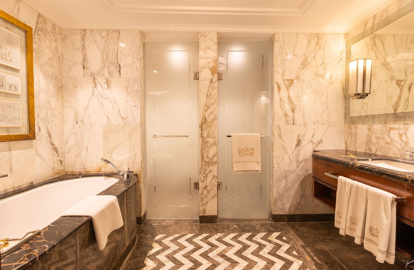 Interior of the Cabana Room bathroom featuring the bathtub, sink, and two glass doors at the front - The Claridges New Delhi