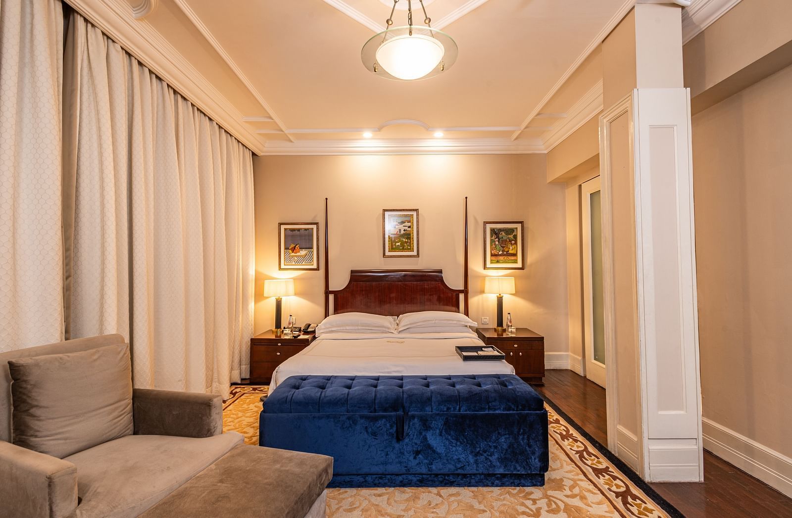 front view of the bed with a blue cushioned seating structure in front of it at our heritage room - The Claridges New Delhi