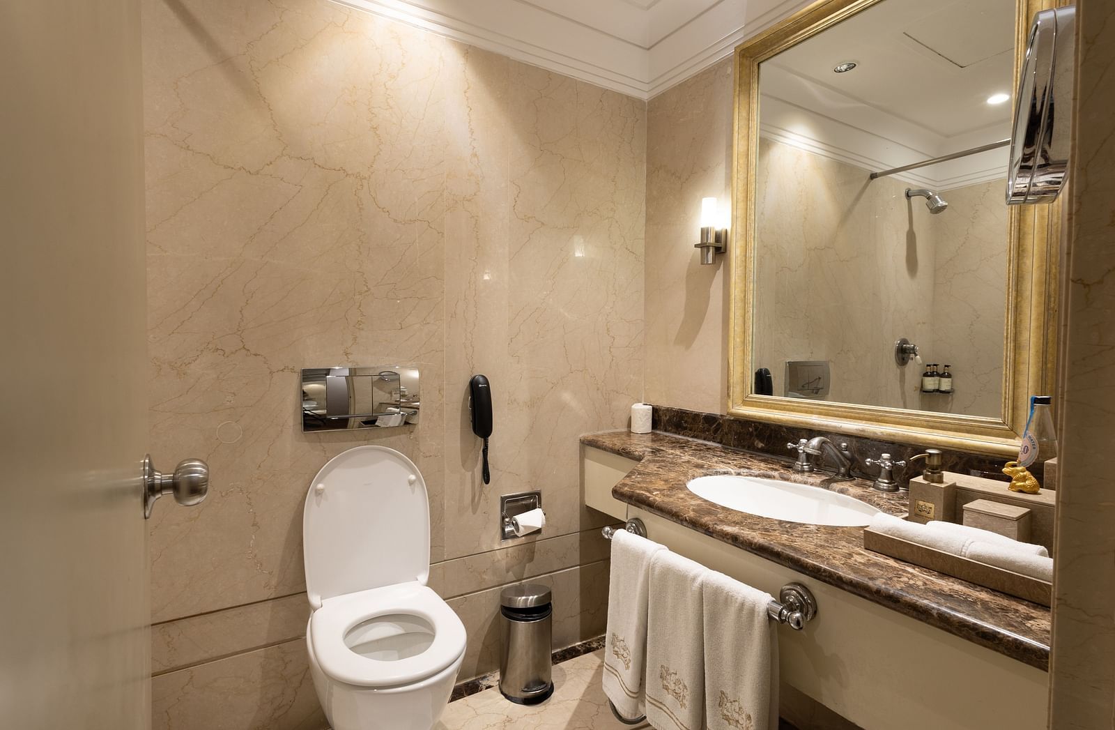 image of the well appointed bathroom with a commode and a sink with a square shaped mirror at the heritage balcony room - image of the heritage balcony room with sleek interiors and a a plush king size bed - The Claridges New Delhi