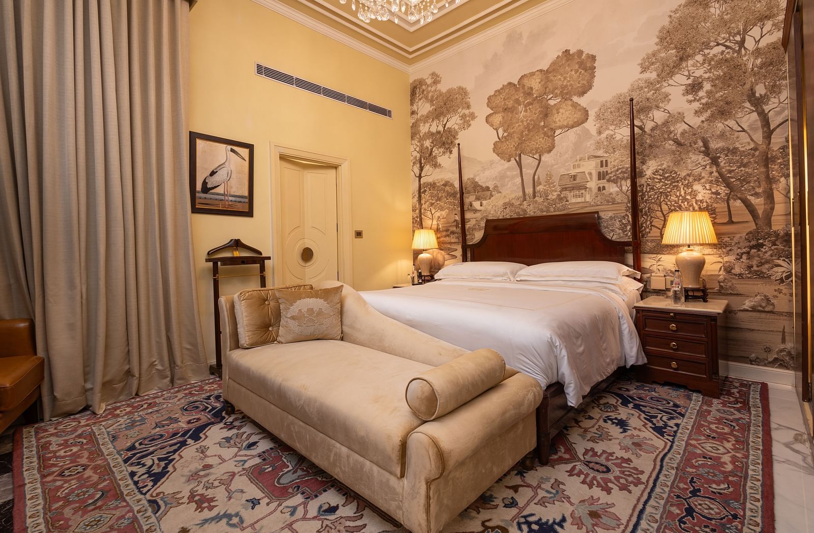 image of a bedroom at our heritage room with a brown scale wallpaper with lush trees - The Claridges New Delhi 
