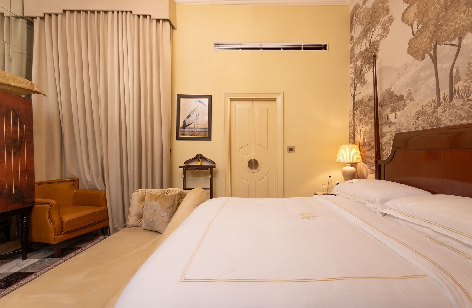 image of the heritage room featuring a king size bed with pale yellow walls in the background - The Claridges New Delhi