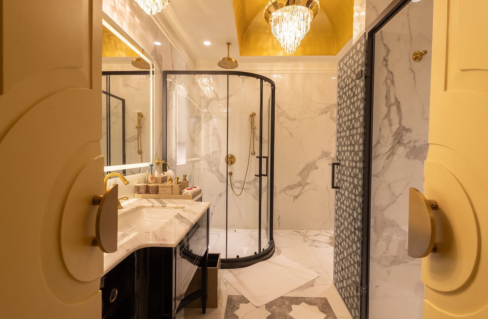 image of the bathroom attached to the heritage room featuring a cubical shower and a chandelier on top - The Claridges New Delhi