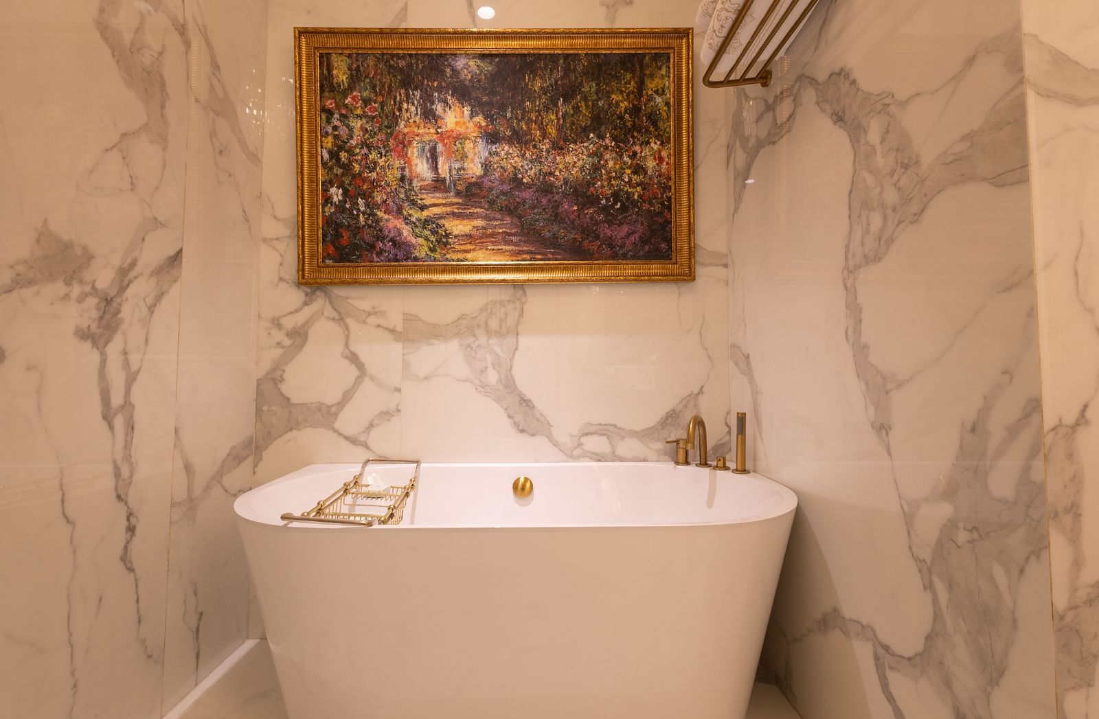 image of the white ceramic bathtub with an amazing golden frame above it - The Claridges New Delhi
