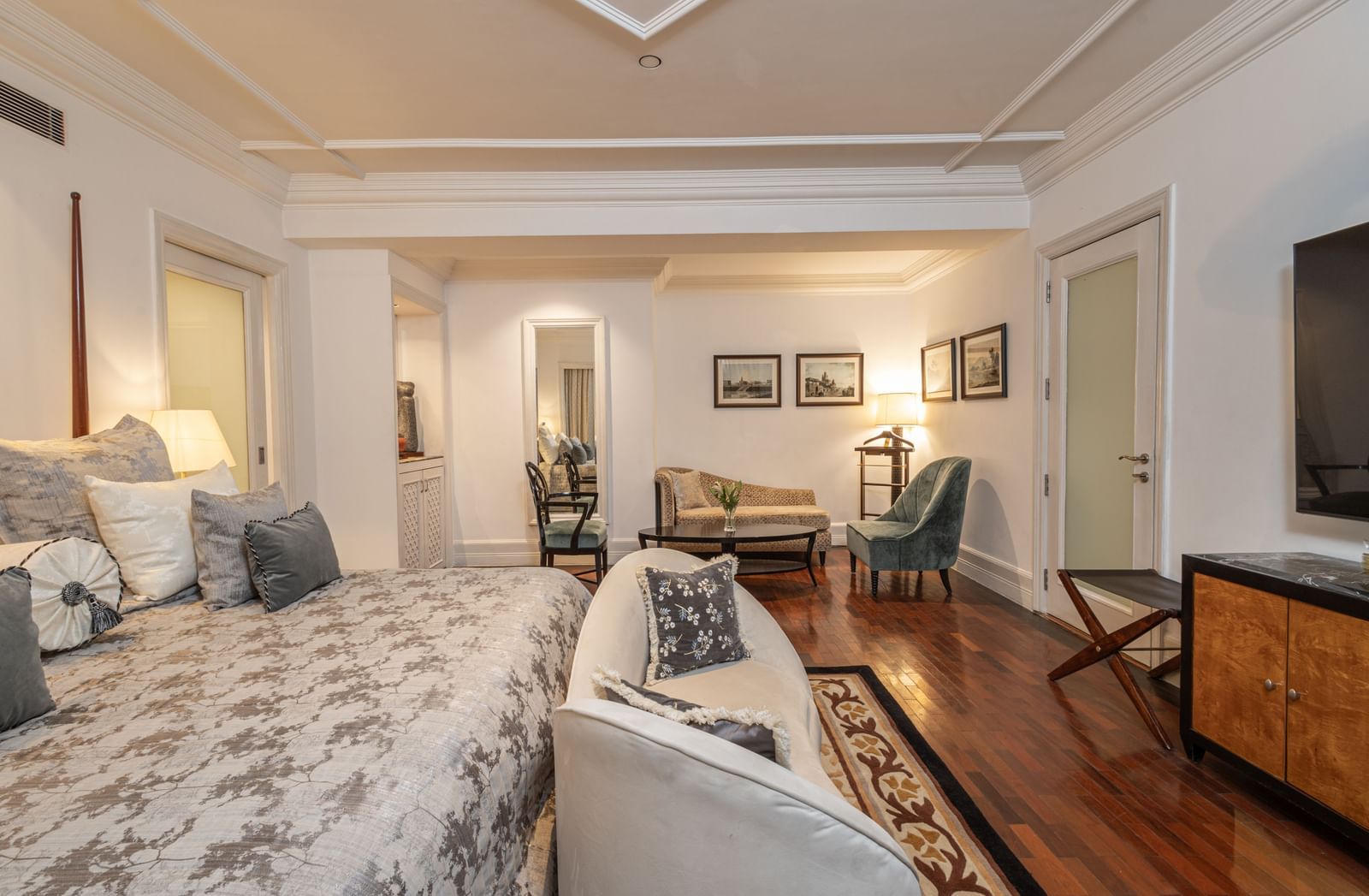 The Claridges New Delhi spacious bedroom with a large bed leads to an adjacent sitting area.