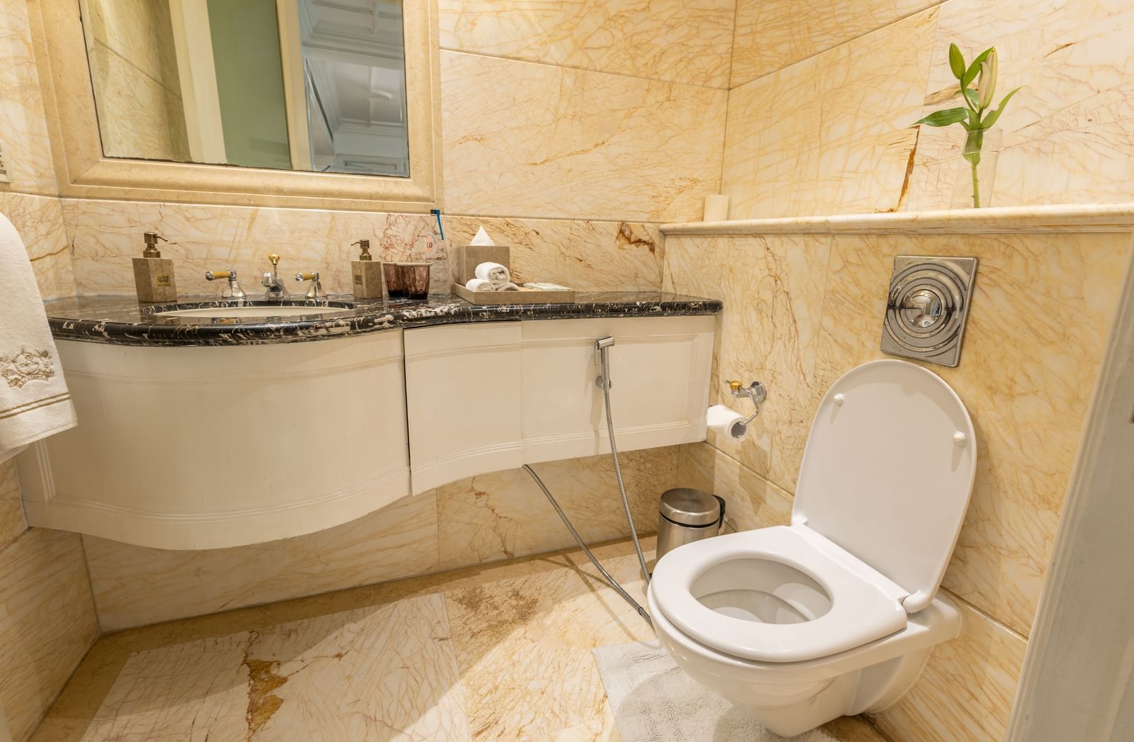 The Claridges New Delhi light-colored marble bathroom shows the toilet and a curved vanity counter.