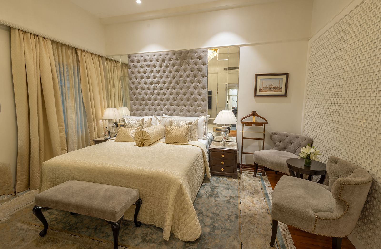 Superior Room at The Claridges New Delhi, featuring a cosy bed with bedside lights and two chairs arranged in the corner