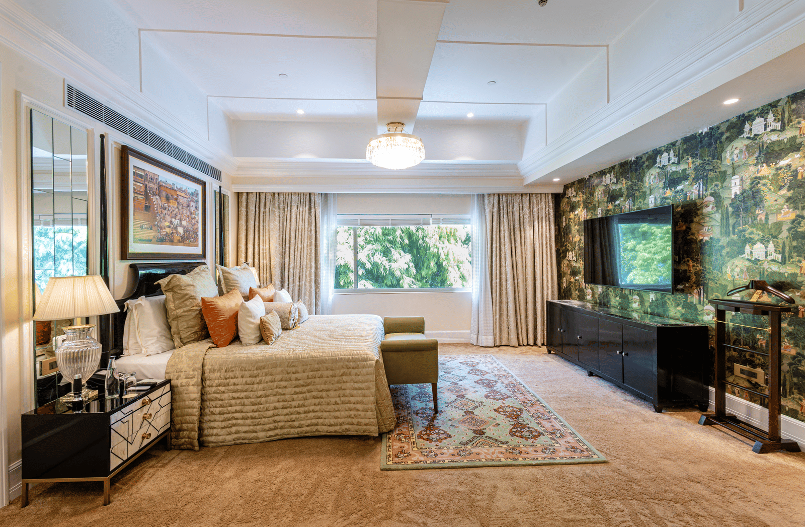 Presidential Suite bedroom featuring a sofa, armchair, coffee table, television, floor lamp, and large windows overlooking greenery at The Claridges New Delhi.