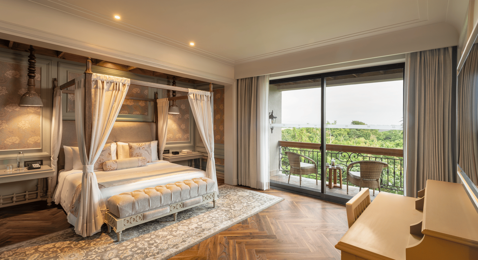 Full-view shot of the bedroom at the Evren Suite featuring wooden flooring and a balcony that opens to the verdant views of the frest at The Evren, Vagator.