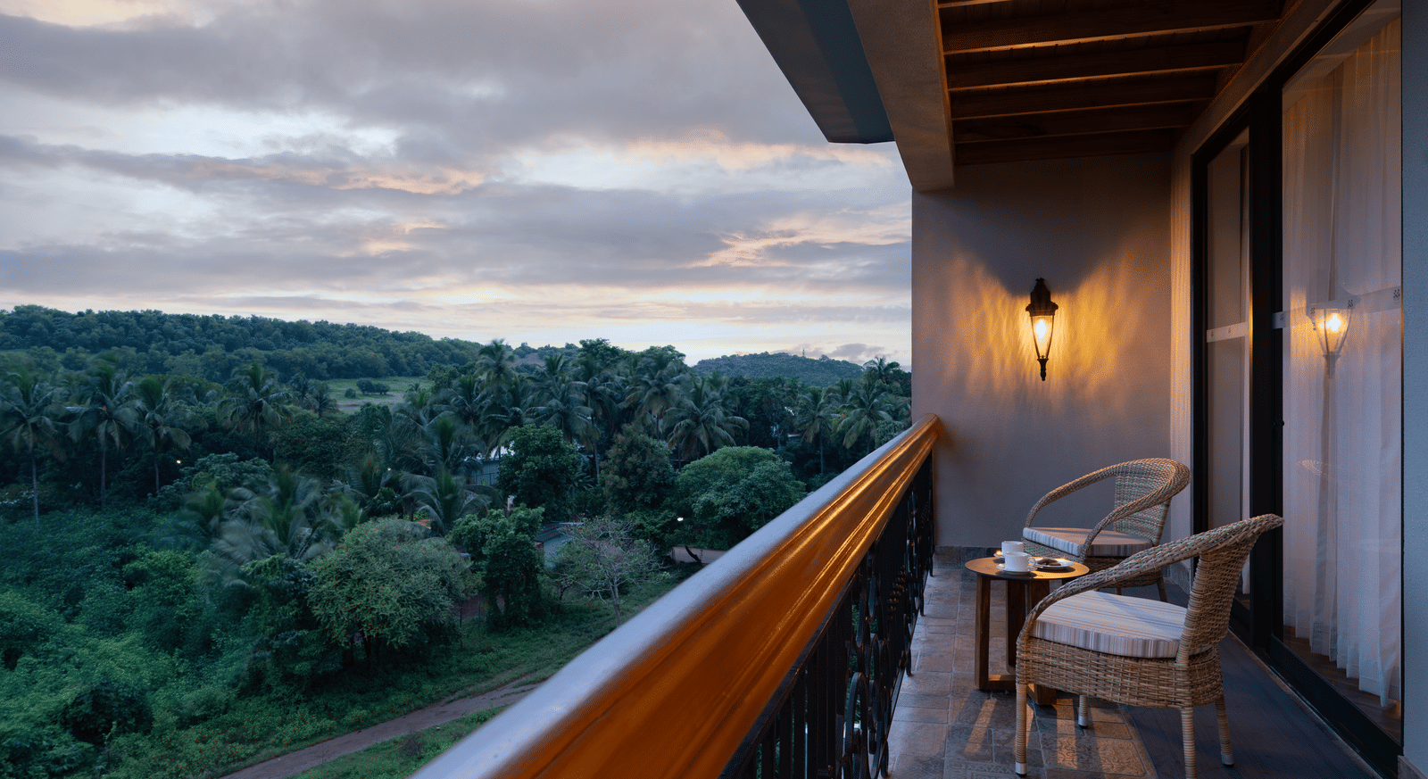 The balcony at the Evren Suite overlooking at the lush green forests with a cloudy evening sky in the background at The Evren, Vagator.