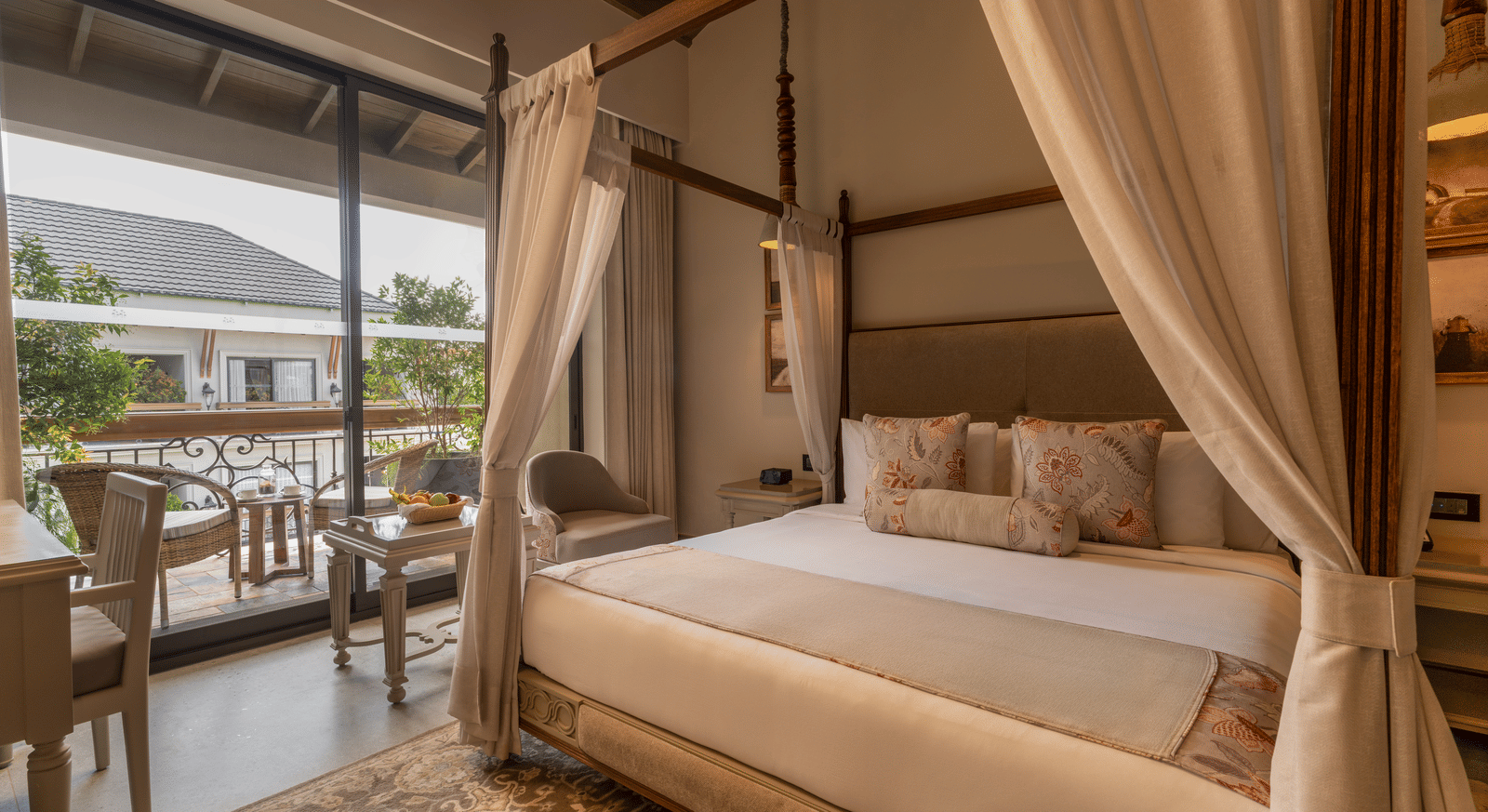 A plush double bed in the Premium Room at The Evren, Vagator, with a balcony beside it featuring a sit-out area.