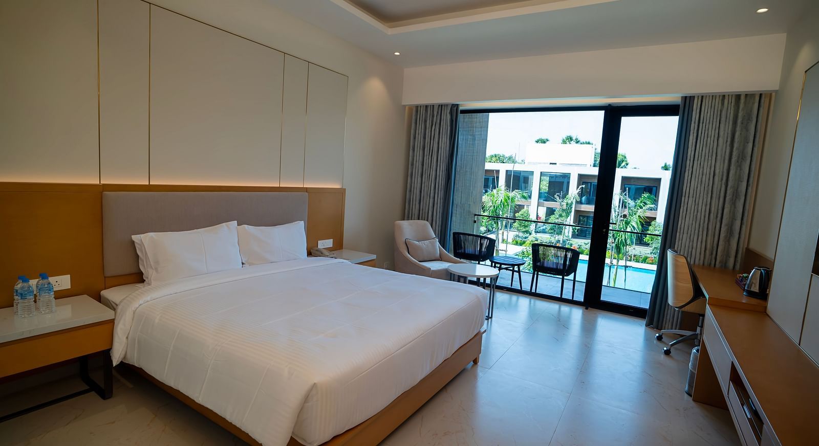 Full view shot of the Pool View Bliss room with tall french windows overlooking the swimming pool at The Shore, Trishvam.