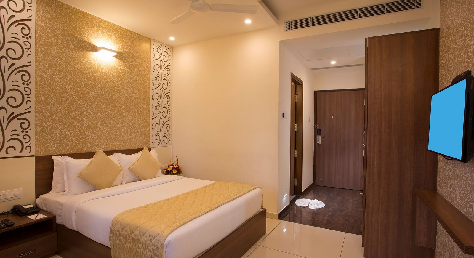 Another view of a hotel bedroom with a plush bed, decorative wallpaper and a view into the hallway - De Venetian by TGI, Brookefield