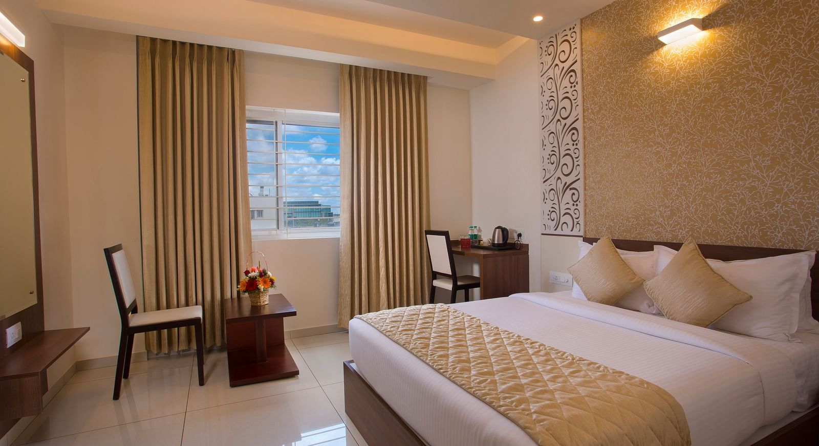 A hotel room with a comfortable bed, a wooden side table with flowers and a city view through the window - De Venetian by TGI, Brookefield