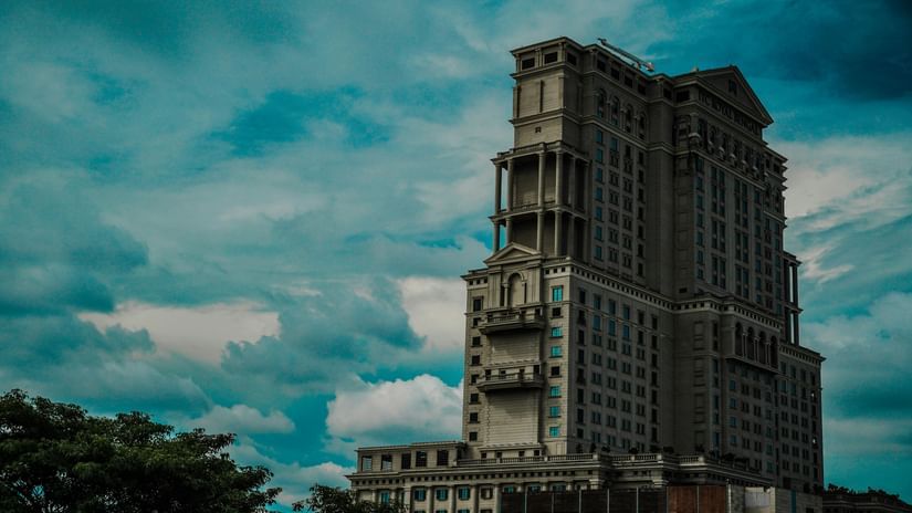 A tall, uniquely designed high-rise building with multiple balconies, set against a dramatic cloudy sky.