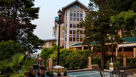 Sundeck and facade of Cedar Inn, Darjeeling featuring picturesque setting, lush greenery.