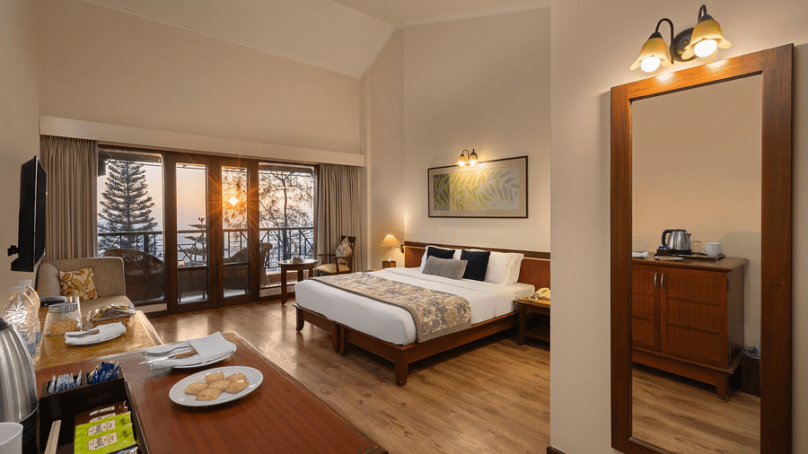 A corner view of Superior Room with plushy bed, table, wall mirror at Baikuth resort, kasauli.