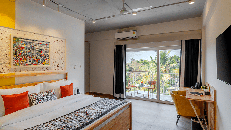 Bright hotel room with, flat TV screen, work desk and chair, vibrant art on the wall, and an access to the balcony at Bedzzz Xclusiv Morjim, Goa