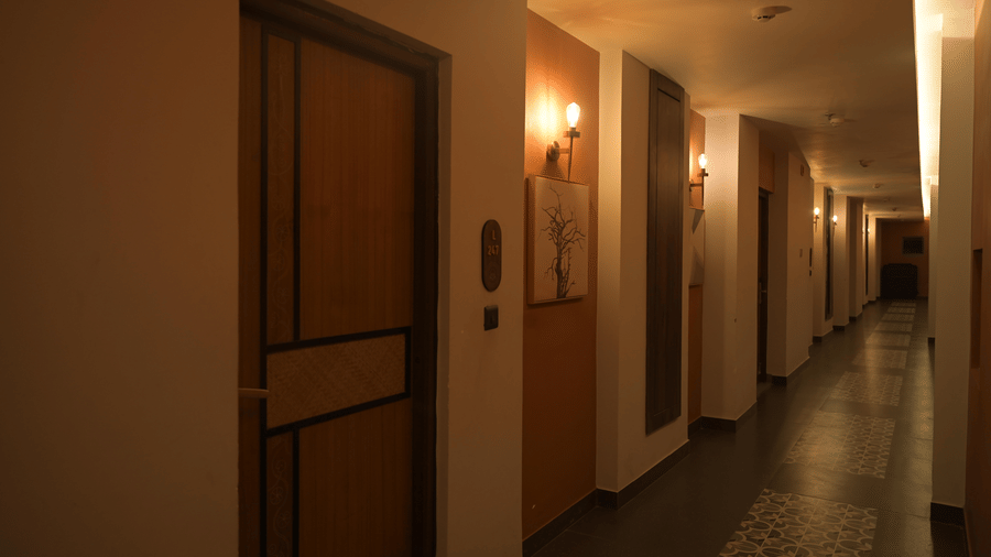 A long well-lit corridor of doors on the left at Hotel Sonar Bangla, Mayapur.