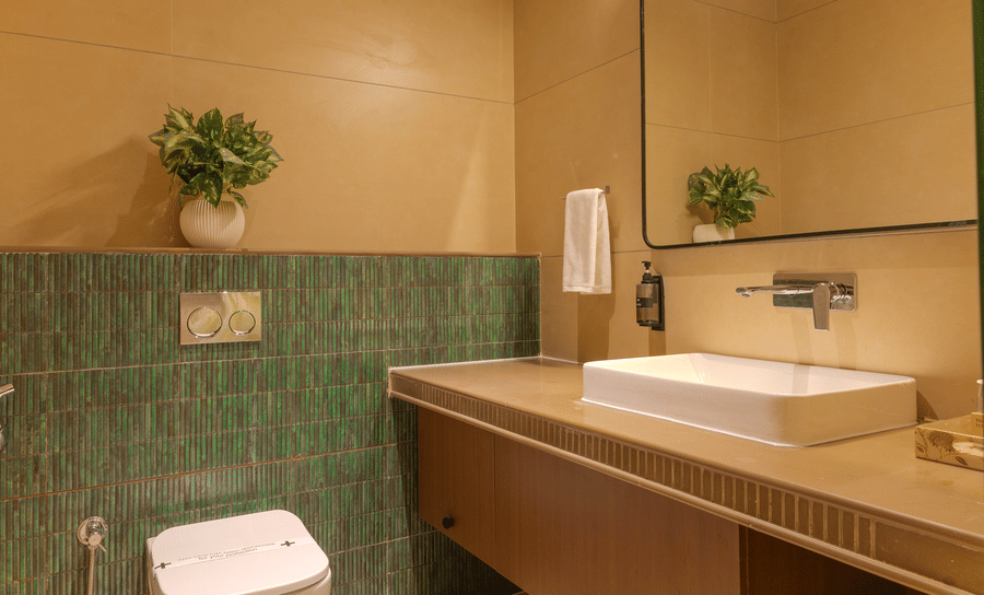 Modern bathroom with a vessel sink, wooden vanity counter and green accent tiles in the Royal Suite at Hotel Bawa, Udaipur.