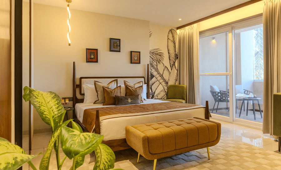 King size bedroom with a cushioned bench, sheer drapes and a sliding door opening to a private balcony at Hotel Bawa, Udaipur