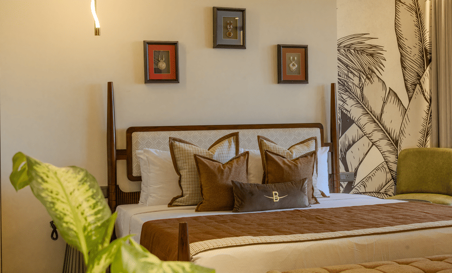 A Sunlit bedroom with a king size bed, decorative cushions and a detailed botanical wall mural in the Suite at Hotel Bawa, Udaipur
