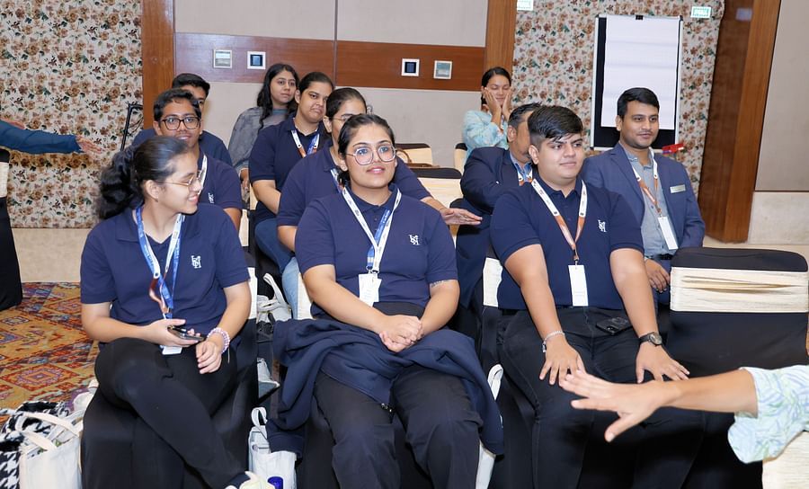 Participants smiling and seated in rows at a session - Karma Lakelands.