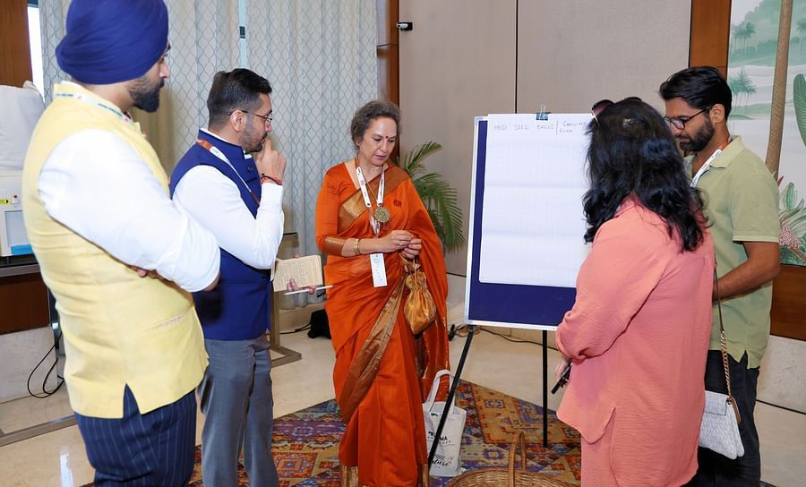 Group of people engaged in a discussion near a presentation board - Karma Lakelands.
