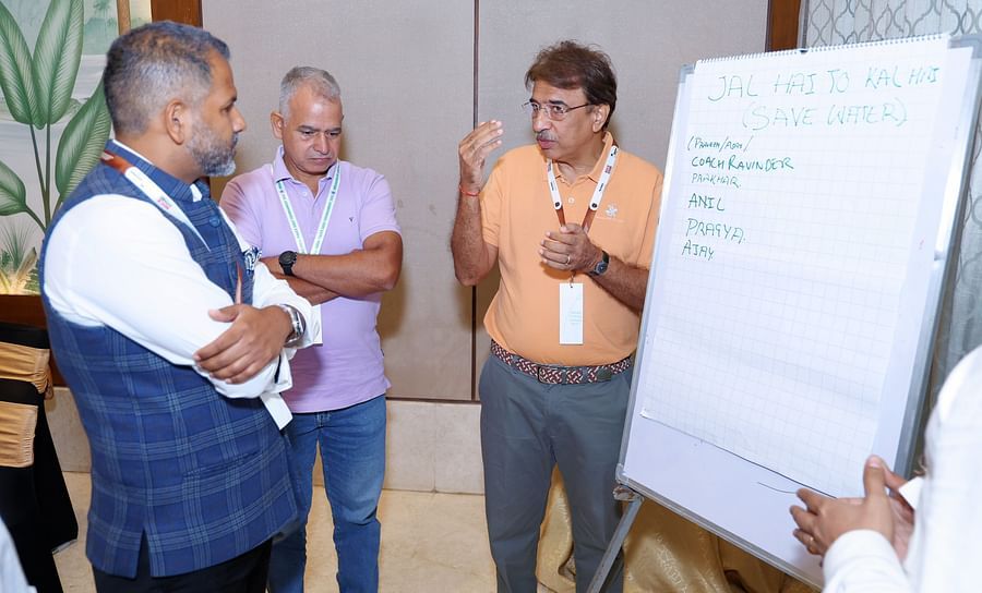 Group of people engaged in a discussion near a presentation board - Karma Lakelands.