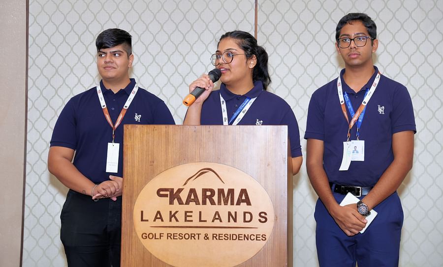 Speaker addressing an audience with a microphone and a few people on the stage - Karma Lakelands.