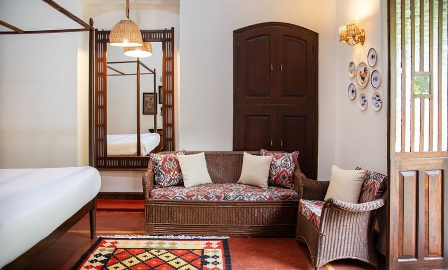 An image of a bed with sofa and wooden doors and hanging lights  at Lamrin Ucassaim Hotel, Goa