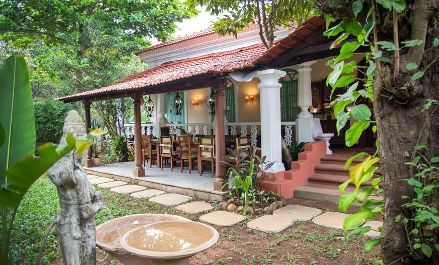 A side view of a cottage style facade image surrounded by trees and plants at Lamrin Ucassaim Hotel, Goa