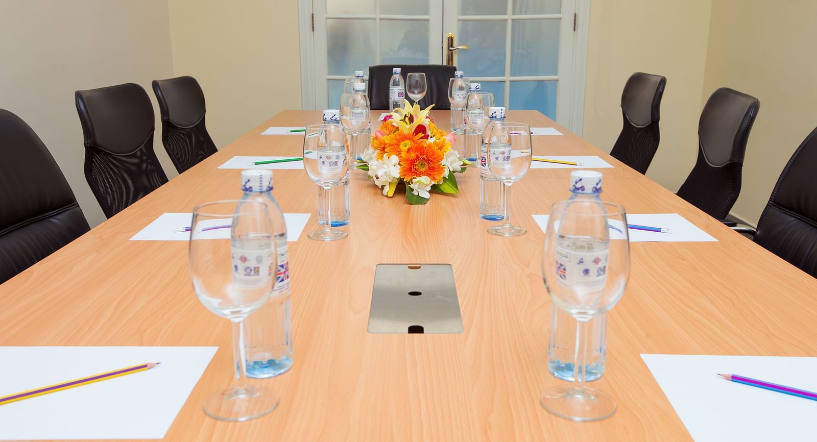 A meeting room with a long table, chairs, and glasses | Conference Hall | Central Mansions, Phnom Penh