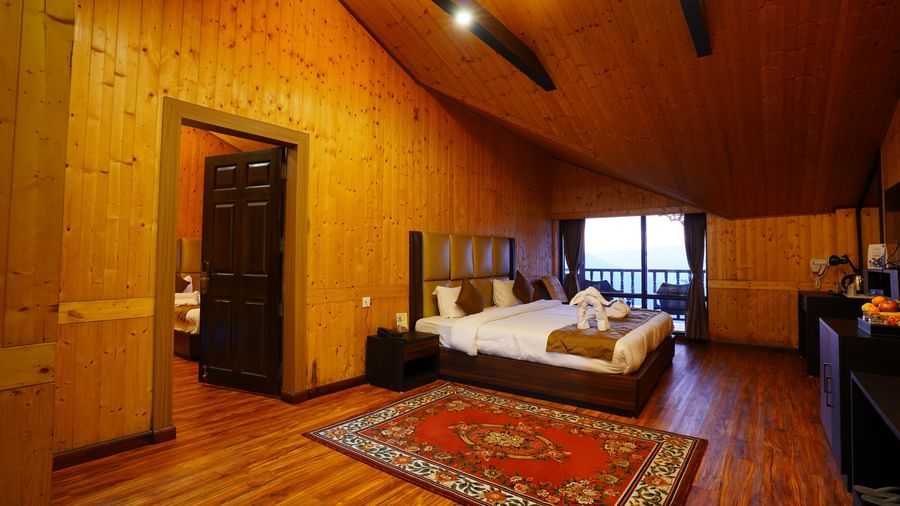 Attic style wooden bedroom featuring a bed, a cabinet table, lights on the ceilings, and a balcony attached at Istana Resort and Spa by Sagar.