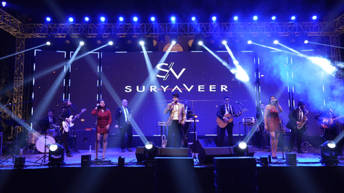 Band performing on a grand stage with captivating lighting and Suryaveer branding.