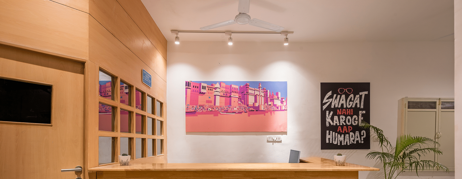 A picture of the reception area at Bedzzz Varanasi, with wooden furnishing and posters on wall.