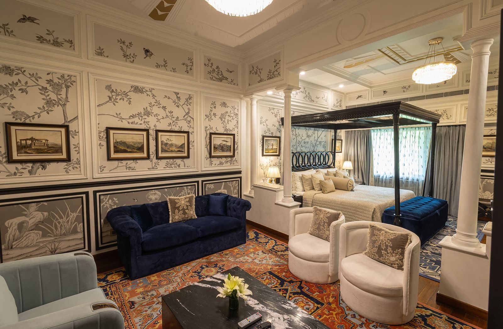 Grand Luxury Room at The Claridges New Delhi, featuring a cosy corner with a plush sofa and a chandelier hanging overhead