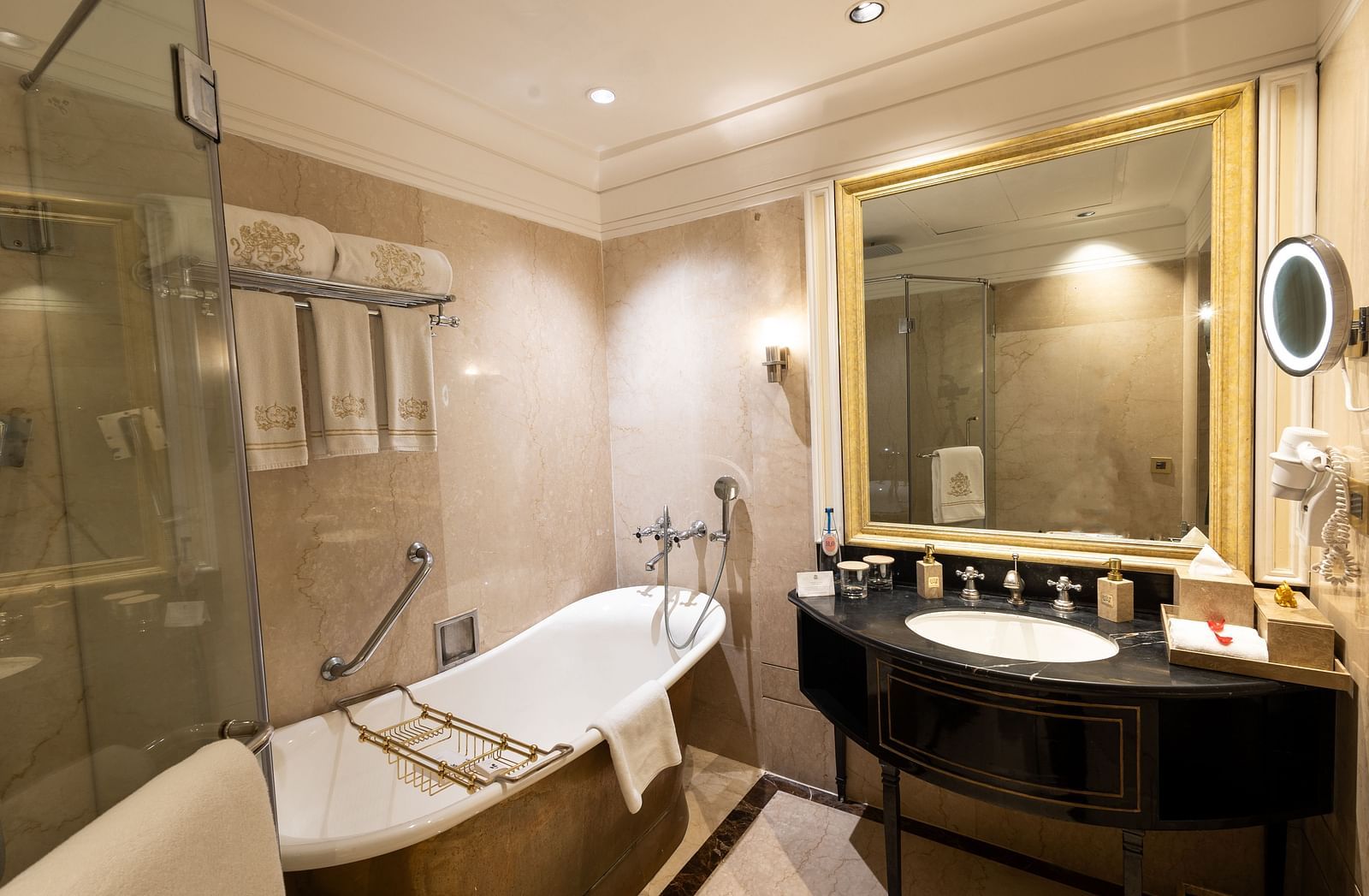 Grand Luxury Room washroom at The Claridges New Delhi, featuring a bathtub, a sleek sink, and a wall-mounted mirror