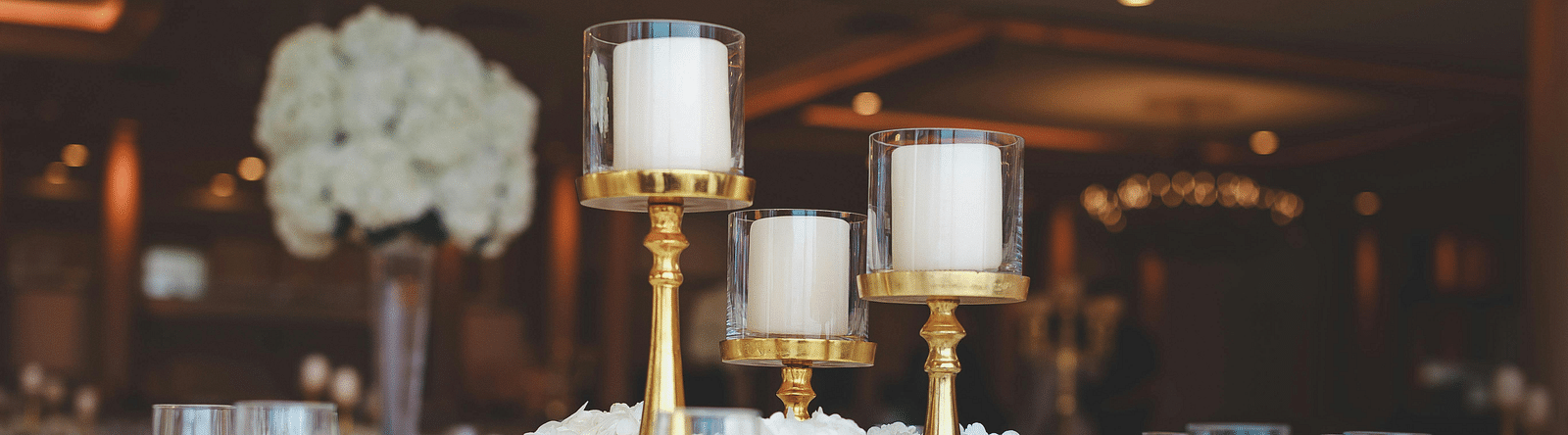 Elegantly set table with glassware, candlesticks and a white decorative object.
