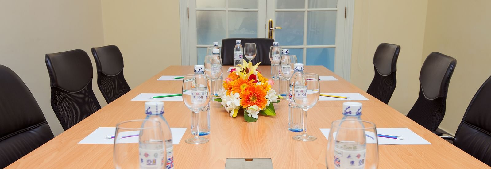 A meeting room with a long table, chairs, and glasses | Conference Hall | Central Mansions, Phnom Penh