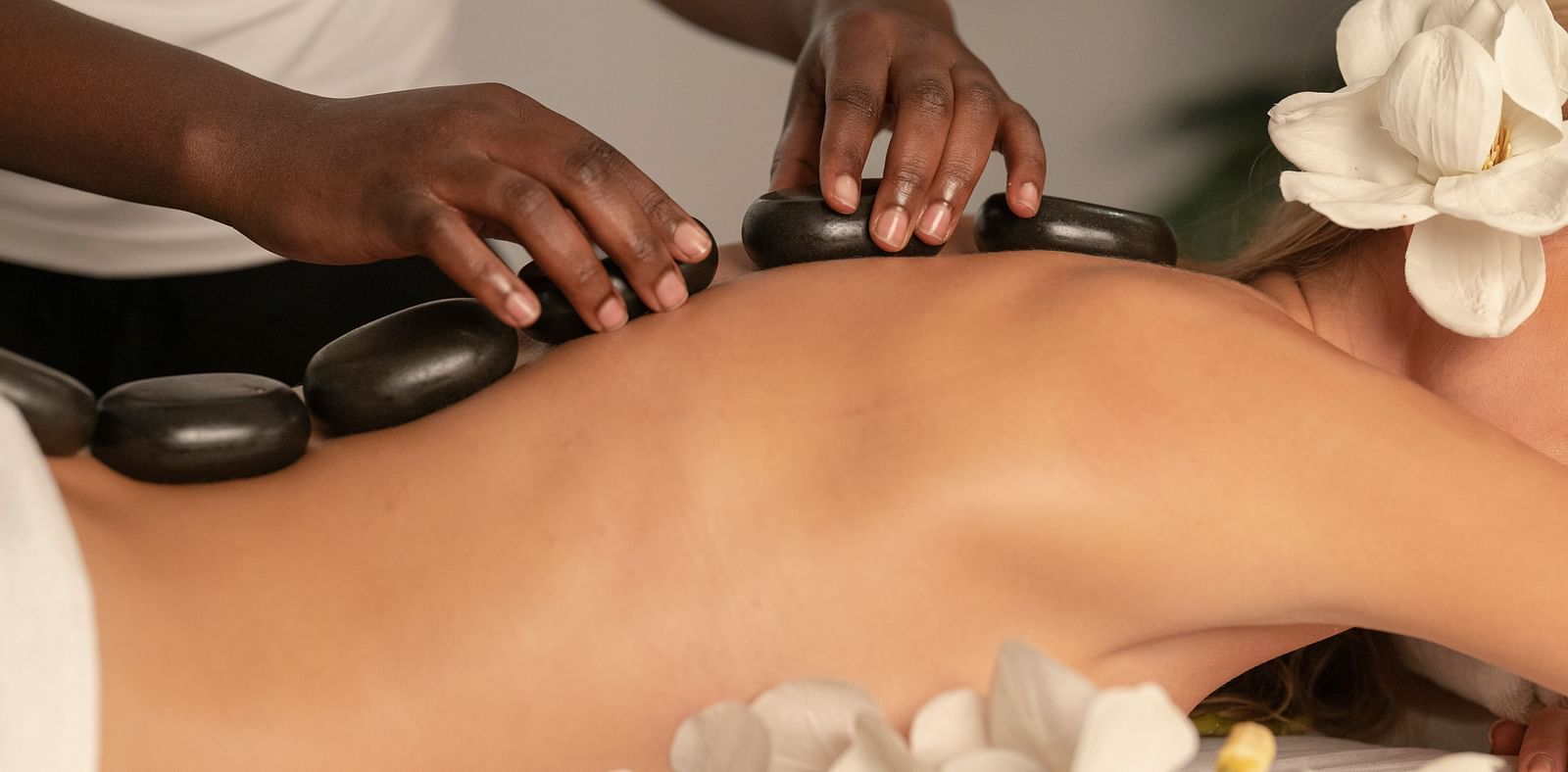 A woman peacefully resting and getting hot stone therapy done in a relaxing spa setting.