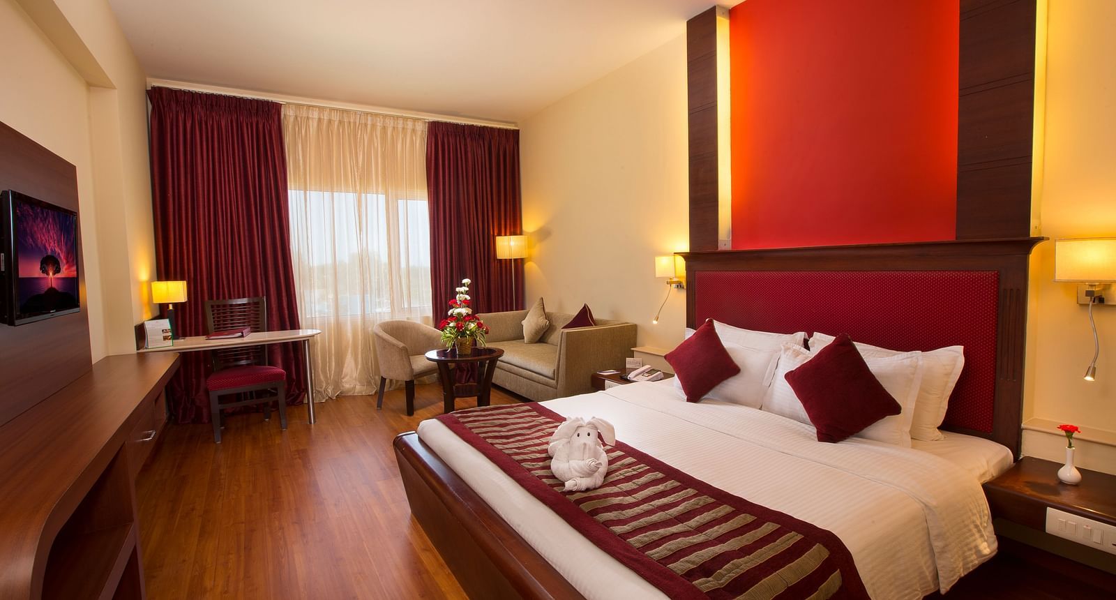 A well-appointed room with a comfortable bed, seating areas, a TV, and lamps.