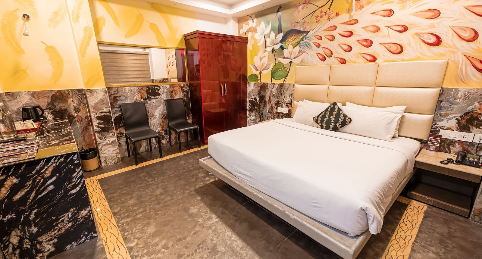 A double bed, chairs and a cupboard at the Deluxe Room at Parakkat Nature Hotel and Resorts Munnar