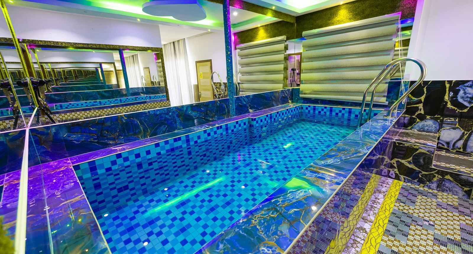 a mini swimming pool surrounded by mirrors on walls on all sides and the entire area is illuminated with different colours of lights - Parakkat Nature Hotels and Resorts, Munnar