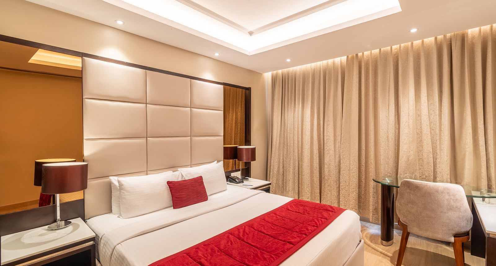 Fortuna suite's bedroom with full-length curtains, bedside table, and armchair- TGI Grand Fortuna, Krishnagiri Main Road, Hosur