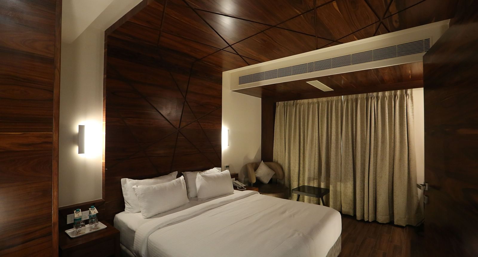 Premium Suite featuring a king size bed, bedside tables, lamps, and dark wood panelling - TGI SPS Grand, Coimbatore